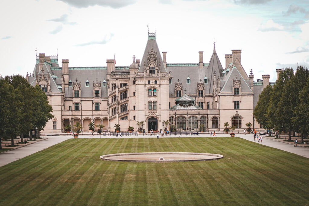 Beige building with grey roof (Biltmore House) and freshly cut lawn in front