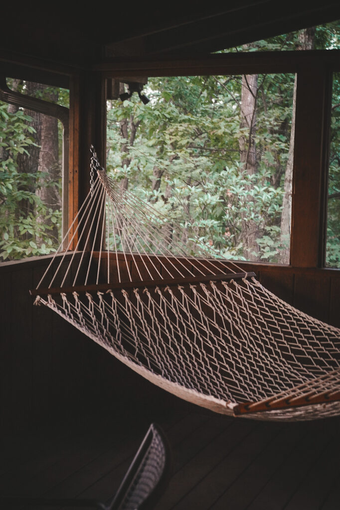 White rope hammock on wooden screened-in porch
