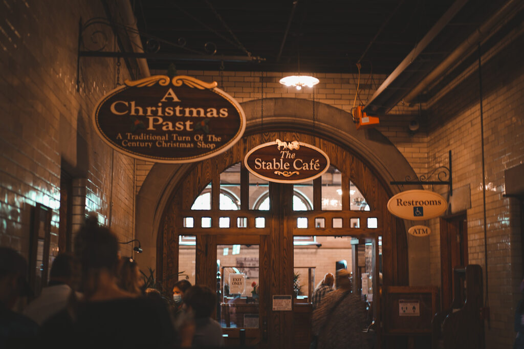 Dark-lit hallway with store sign that read “A Christmas Past” and “The Stable Cafe”