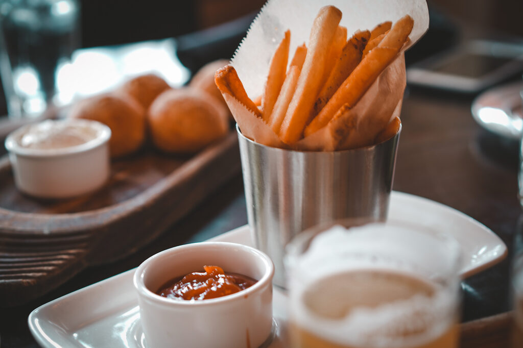 Serving of fries in silver cup with a side of ketchup in a small white cup