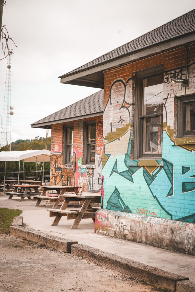 Brick buildings with multi-colored graffiti and wooden picnic tables in front of building
