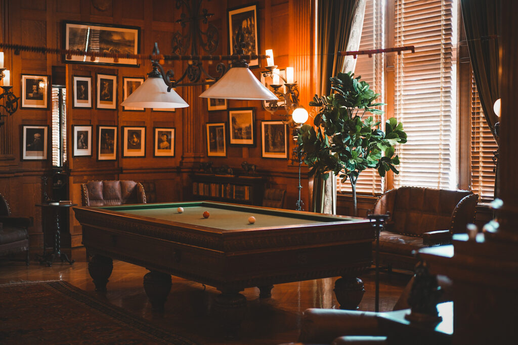 Dark-lit room with pool table and chairs around it
