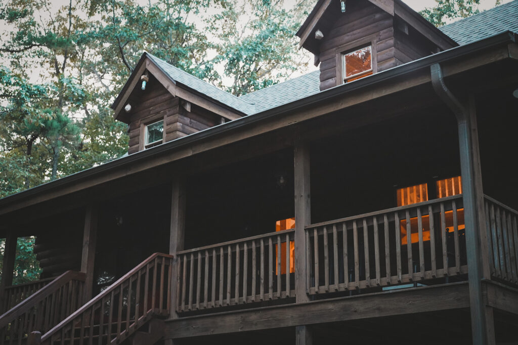 Dark brown wooden cabin with front porch and stairs leading up to it