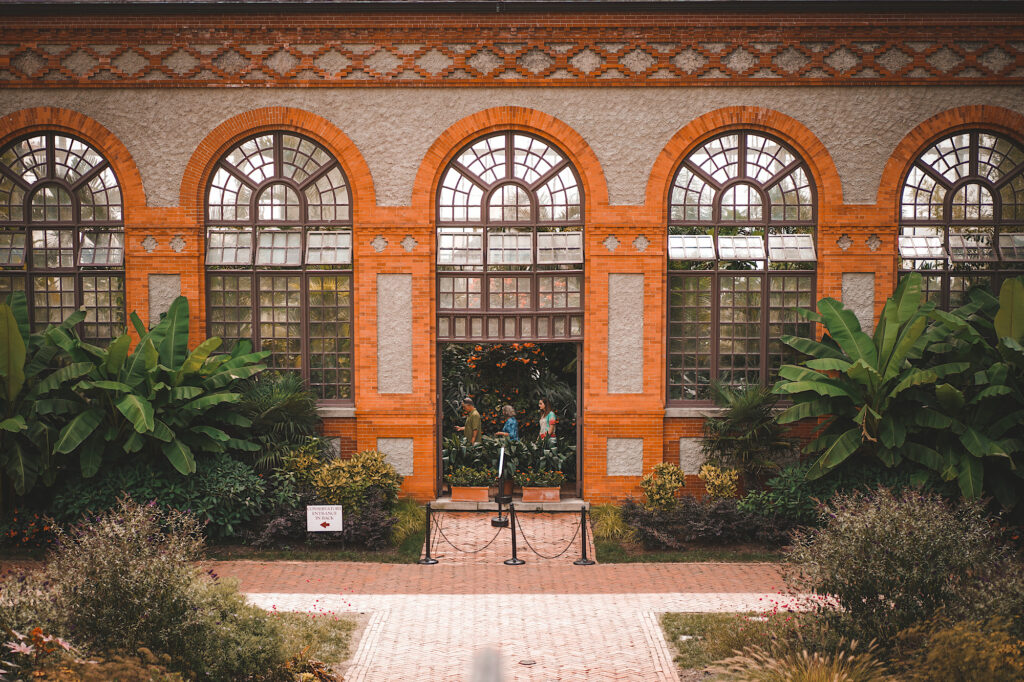 Orange and beige brick building with large plants on the outside and inside